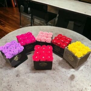 A table with six different colored boxes of flowers.