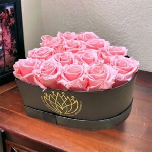 A box of pink roses on top of a table.