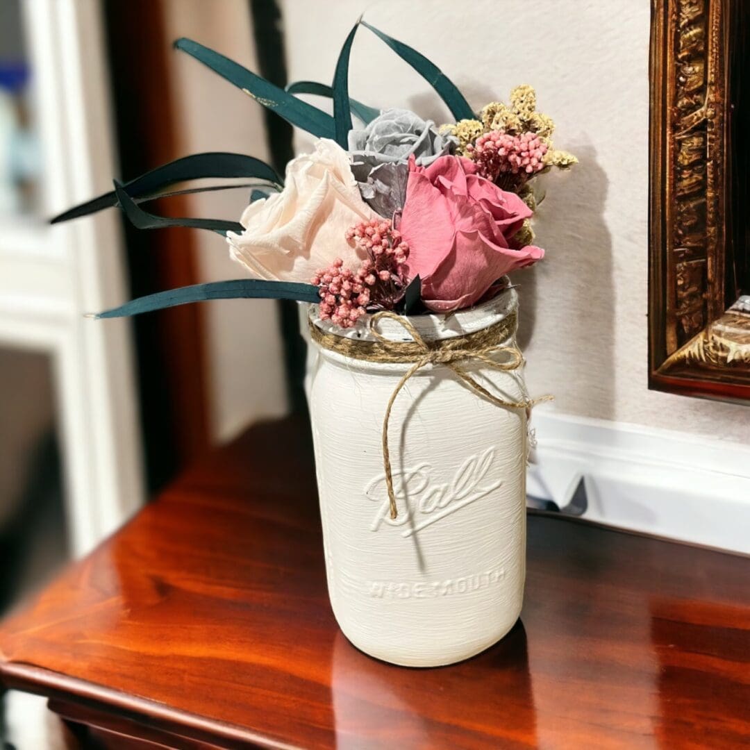 A mason jar with flowers in it on top of a table.