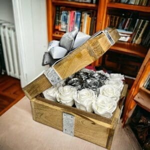 A wooden box filled with white roses and ribbon.