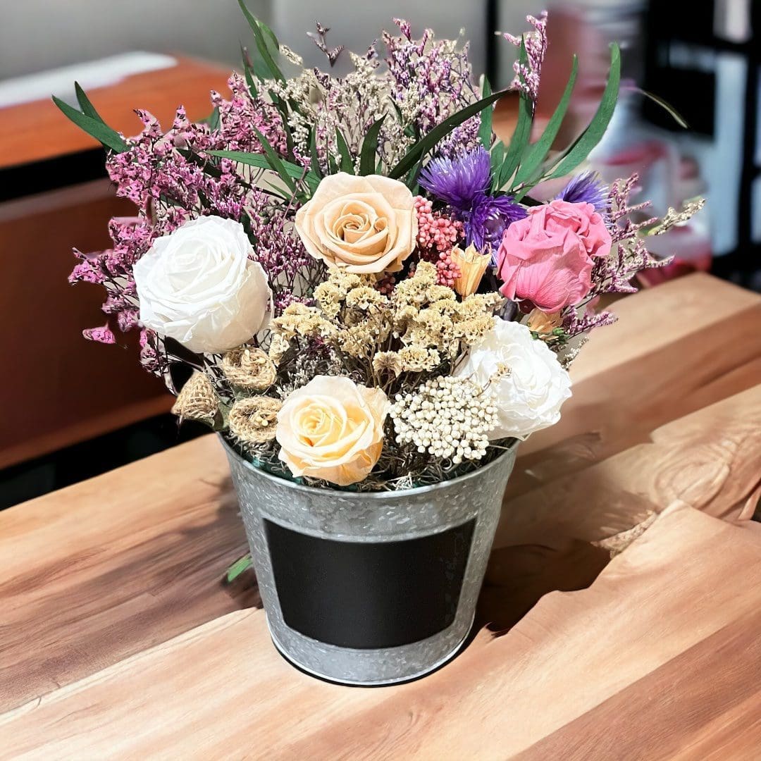 A table with flowers in a bucket on it