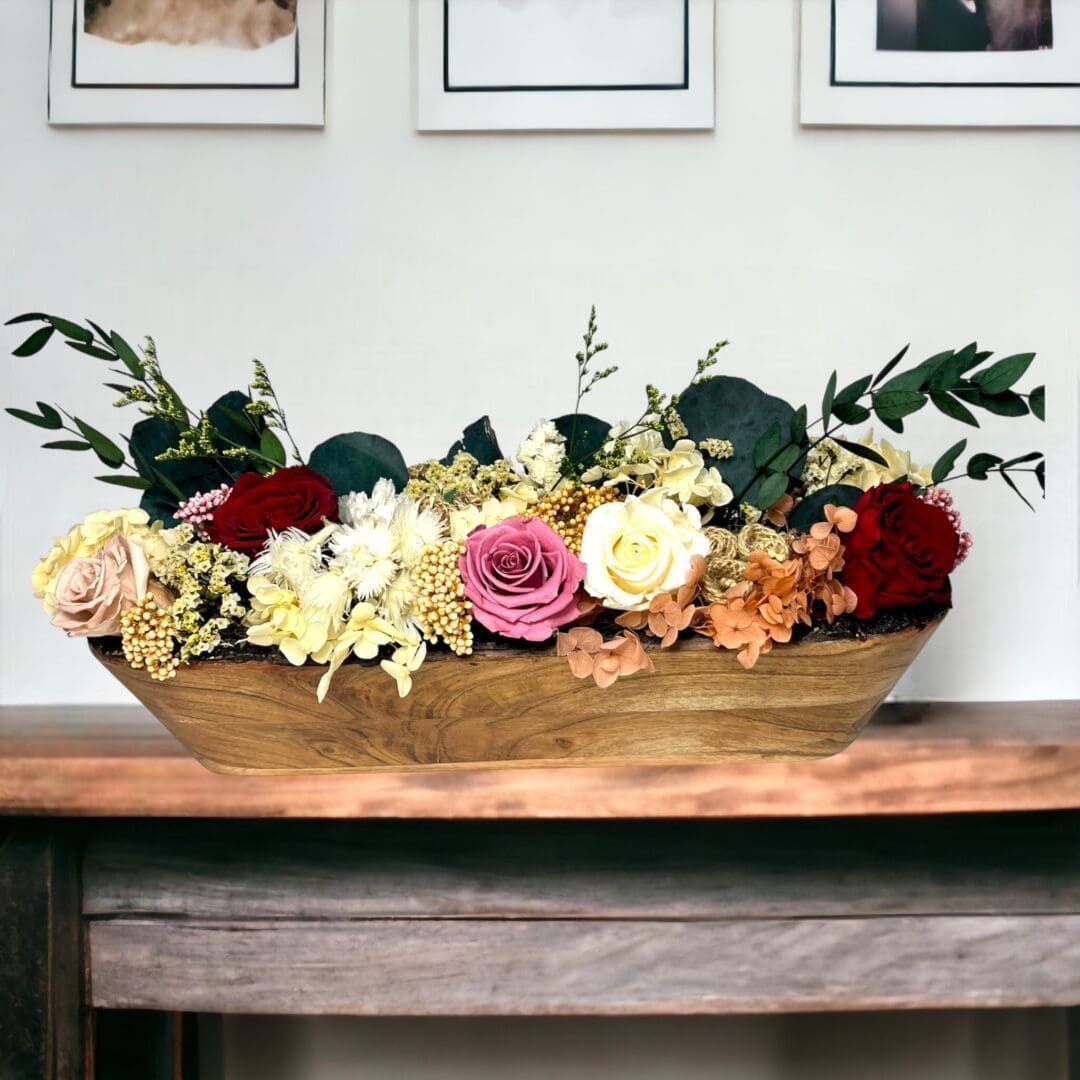 A wooden bowl filled with flowers on top of a table.