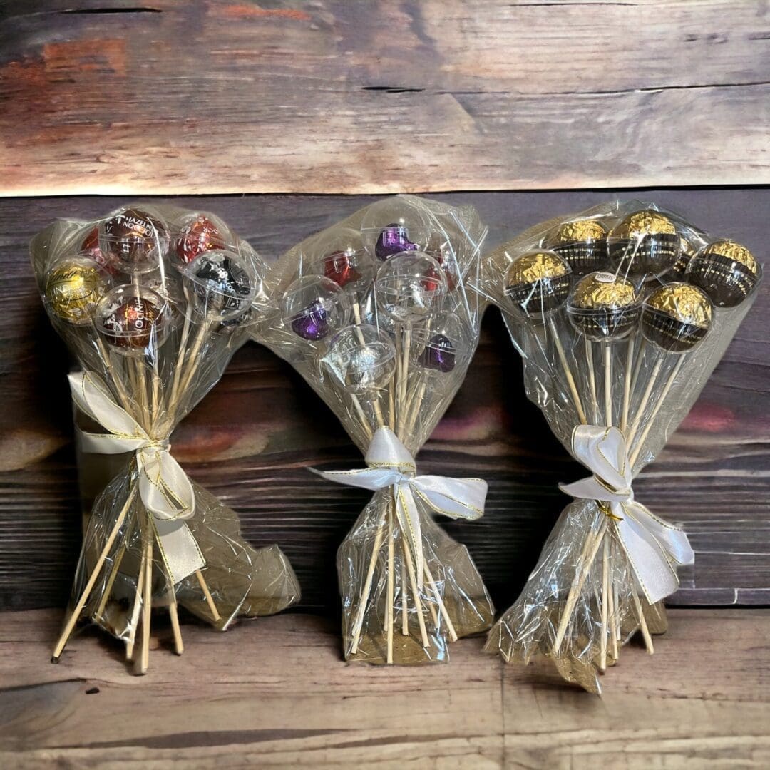 Three lollipops wrapped in plastic tied with ribbons.