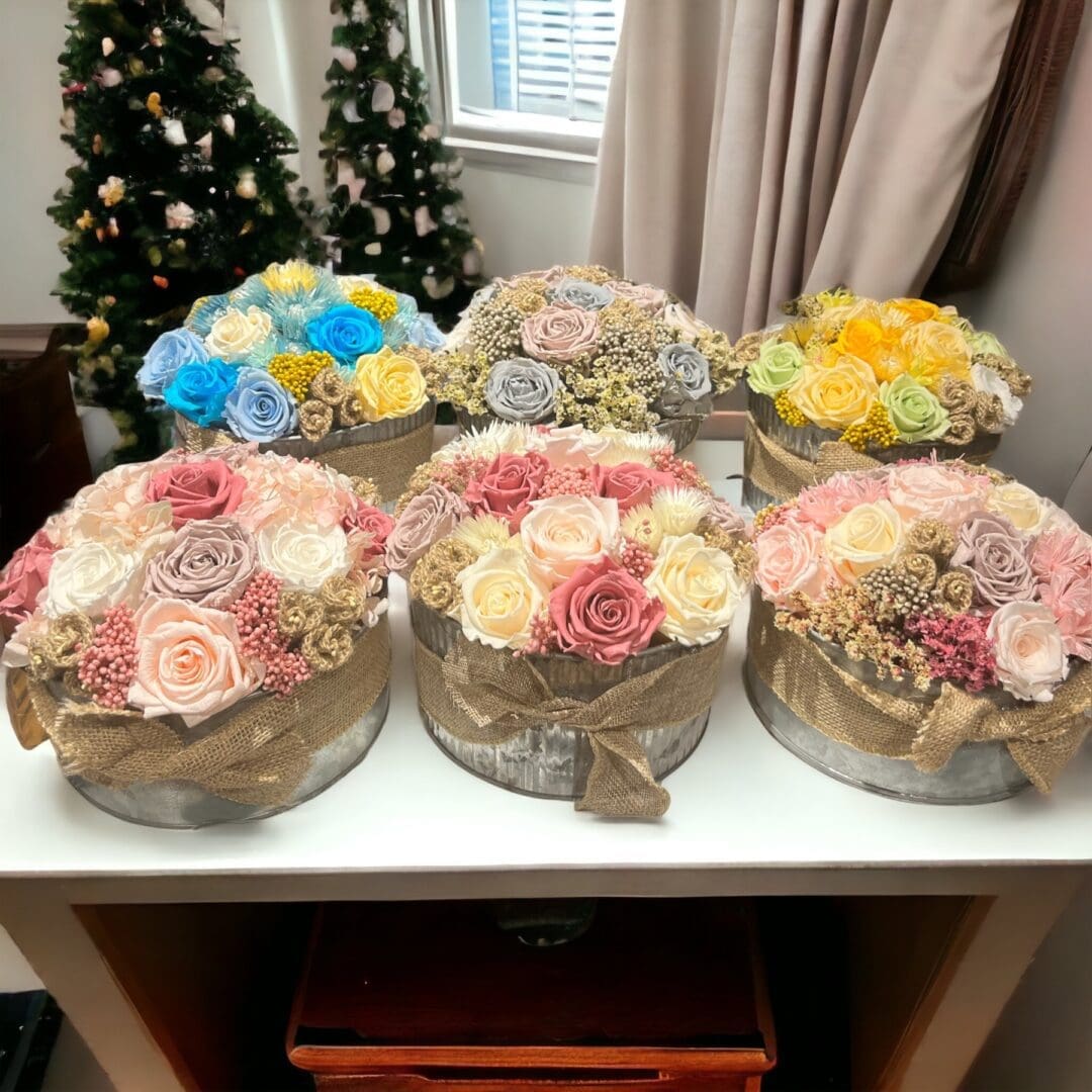 A table with six round boxes of flowers on it.