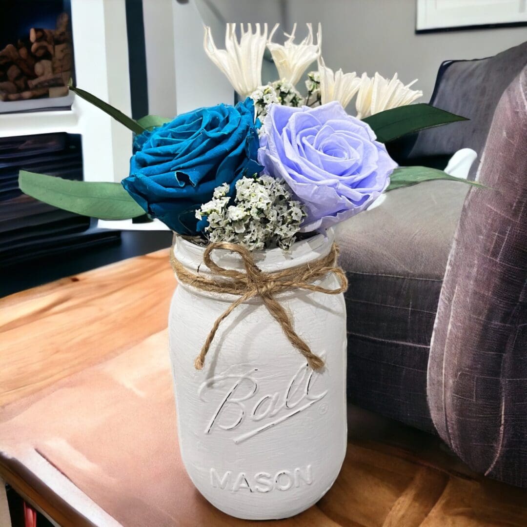 A mason jar with flowers in it on top of a table.