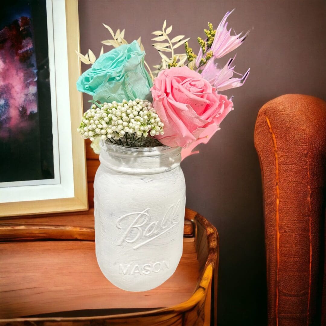 A mason jar with flowers in it on top of a table.
