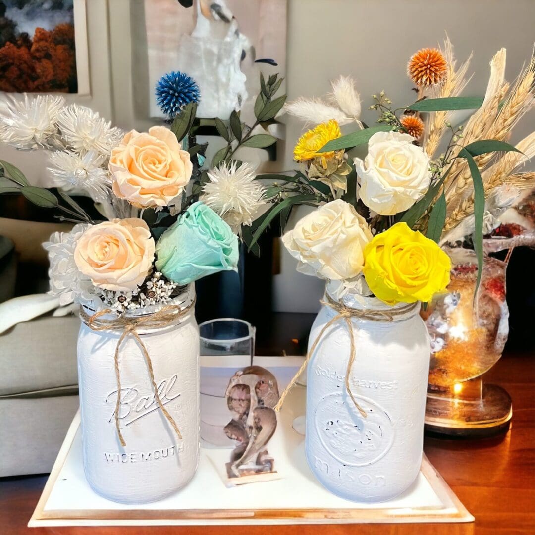 A table with two mason jars and some flowers.