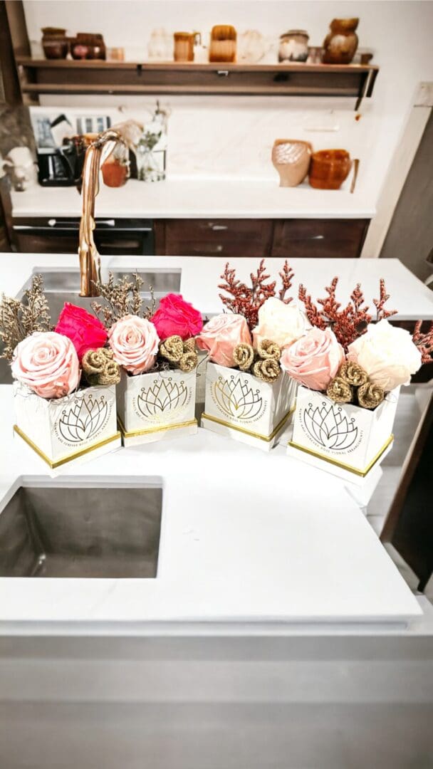 A counter with four different flower arrangements in it.