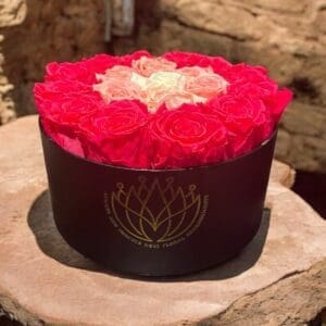 A round box of roses on top of a wooden table.